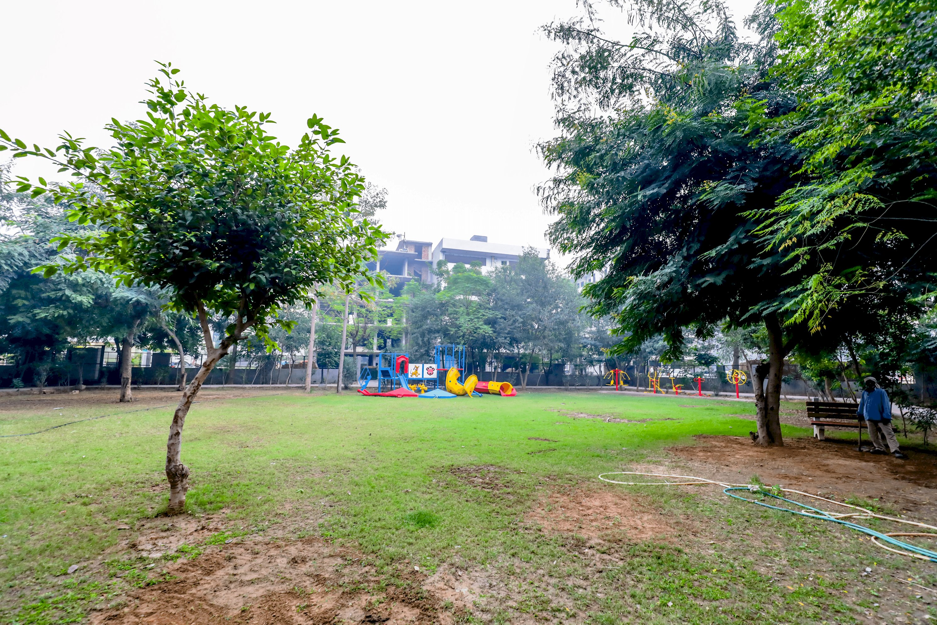 A vibrant park scene featuring children enjoying rides and games, with colorful play equipment and joyful laughter filling the air
