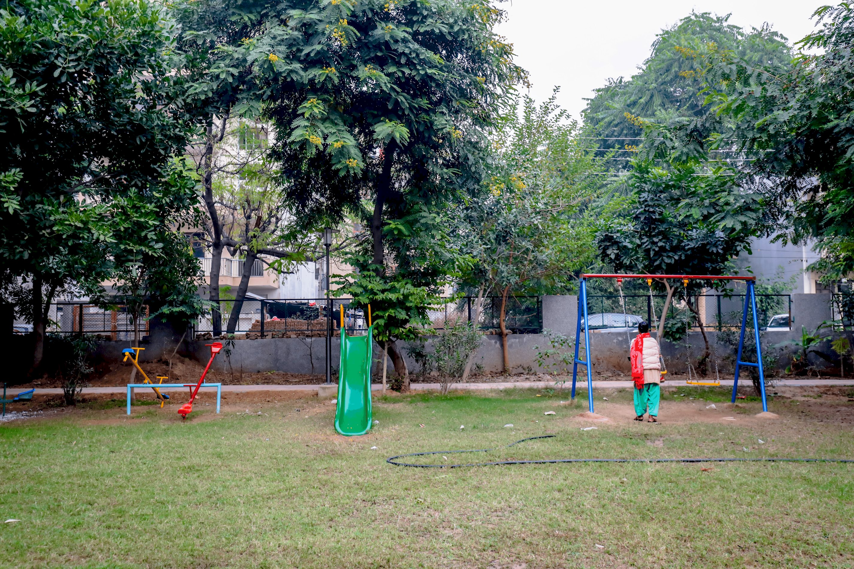 A vibrant park scene featuring children enjoying rides and games, with colorful play equipment and joyful laughter filling the air
